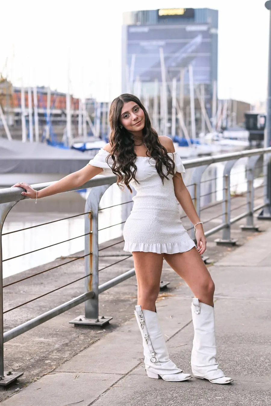 Luana sonriendo, de vestido blanco, junto a la costanera